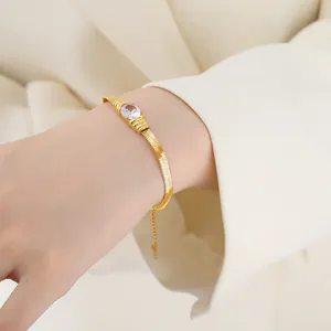 Elegant gold snake chain bracelet with oval zircon and teardrop charm on female wrist