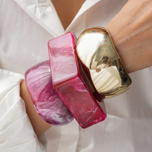 Detailed stack of geometric resin marble bangles and a gold mirror metal wide cuff