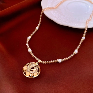 Détail du collier de perles à disque en zircon sur soie rouge avec pendentif doré