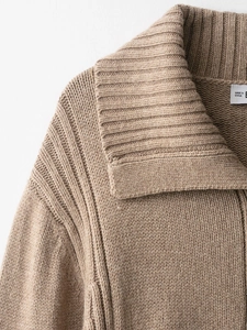 Detail shot of camel chunky knit sweater featuring lapel design and inner garment label