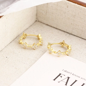 Close-up of gold s925 silver four-leaf clover huggie earrings with sparkling crystals