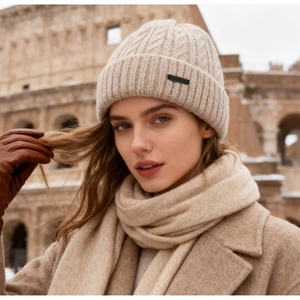 Detail of beige cable knit beanie with logo tag paired with winter accessories