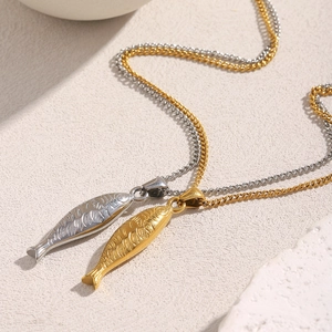 Détail des pendentifs saumon en or 18 carats et argent avec écailles sur chaînes gourmette