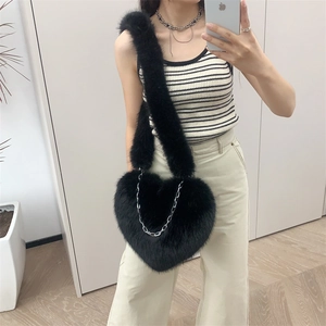 Close-up of heart-shaped black plush crossbody bag with a silver metal chain strap