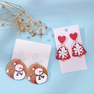 Detail of acrylic Christmas earrings with snowman and red heart bell on blue background