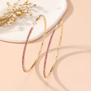 Detail of gold-plated hoop earrings with pink zircons on marble display