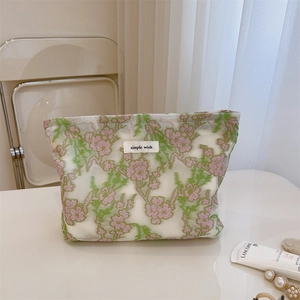 Detail of floral embroidery on mesh makeup bag with simple wish label and zipper