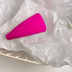 Detailed close-up of a pink triangular sponge hair clip on white textured paper
