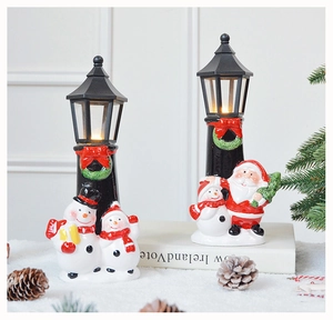 Close-up of lighted LED Christmas lantern figurines with snowman and Santa on snow
