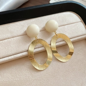 Detail of silver needle brushed metal oval earrings with resin beads in a velvet jewelry box