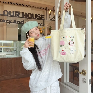 Detail view of Peach Puppy embroidery on beige canvas tote bag with cute cartoon patches