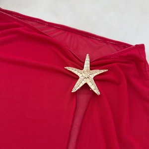 Detail of dark red mesh fabric with a premium golden starfish metal buckle accent