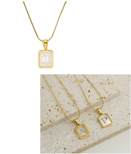 Detail of gold-plated stainless steel necklace featuring a white shell letter pendant