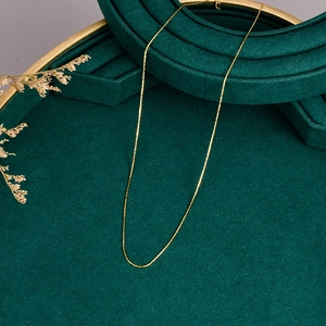 Minimalist gold ultra-thin stainless steel necklace chain on dark green velvet tray