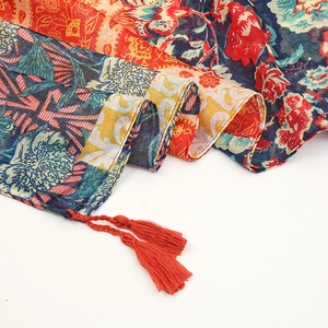 Bohemian floral print scarf with colorful patterns and red tassels on white background
