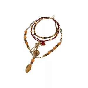 Bohemian multi-layer necklace with beaded chains, red woven cord and vintage gold charms