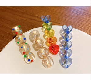 Detail shot of colorful beaded hair clips with polka dots and gradients on a white plate