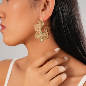 Detail of artistic hollow flower earring with metallic golden finish on a fashion model