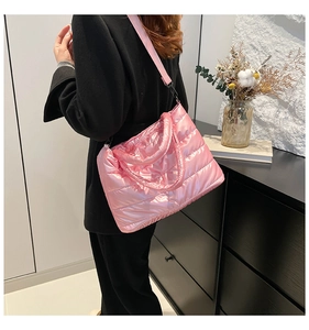 Detail of pink quilted puffer shoulder bag in glossy nylon fabric worn by model