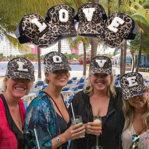 Close-up of leopard print trucker hats with glittery LOVE letter patches on mesh back
