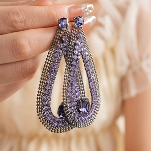 Detail of vintage drop earrings with purple rhinestones on a dark metal mesh base