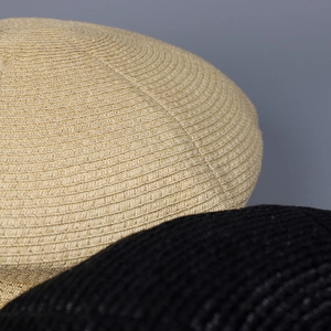 Close-up of natural beige and black woven newsboy caps showing detailed spiral texture