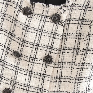 Elegant black and white tweed two-piece set with floral buttons and frayed edges