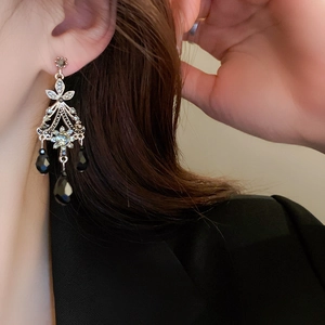 Macro detail of vintage palace earrings featuring hollow patterns and black teardrop beads