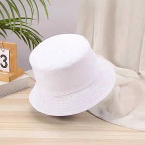 Detail view of a white minimalist cotton bucket hat on a wooden desk with green plants