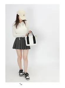Detail of canvas tote bag with black straps worn by a model in casual style