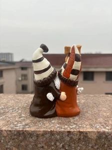 Detailed view of coffee-themed hugging gnome resin figurines on outdoor stone ledge
