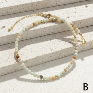 Detailed macro view of beaded necklace with green malachite stones and golden lobster clasp