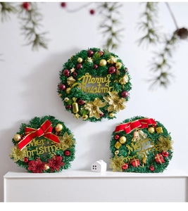 Detail of three Christmas pine wreaths with red bows, gold bells and Merry Christmas signs