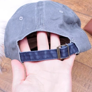 Detail of adjustable metal buckle and strap on vintage washed grey baseball cap