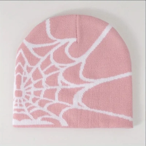 Close-up of the pink knitted beanie showing the white spider web jacquard pattern detail