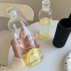Minimalist transparent water bottle with time markers and lemon water held in hand