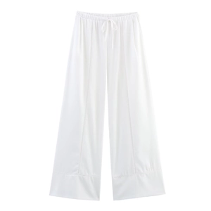 Detail of white linen wide-leg pants with drawstring waist and hollow out embroidery