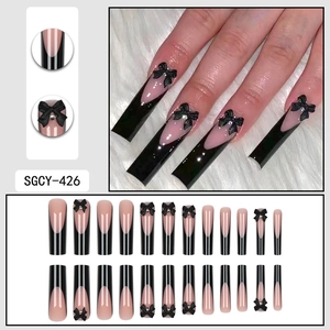 Longs ongles carrés French avec nœuds noirs et strass sur base rose poudré
