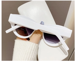 Detail of white cat-eye sunglasses with purple lenses and thick stylish frames