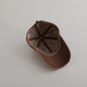 Close-up of brown washed denim baseball cap interior showing six-panel seams and care label
