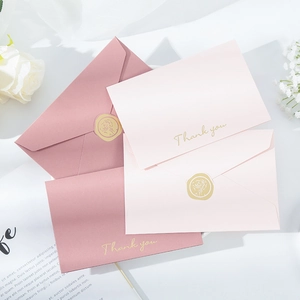 Macro view of gold foil Thank You cards and pink envelopes with rose wax seal pattern