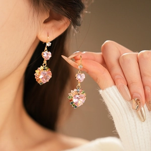 Detailed view of pink heart-shaped earrings with colorful zircon stones on model