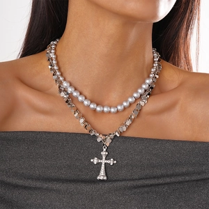 Close-up of double-layer necklace with silver pearls and rhinestone cross pendant