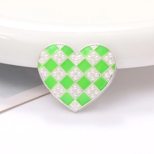 Detail of heart-shaped zinc alloy charm with green checkered enamel and pearls