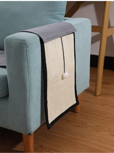 Sisal cat scratching mat hanging on sofa armrest with interactive white pom-pom ball detail