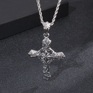 Macro shot of silver ornate cross pendant with relief patterns and twisted rope chain