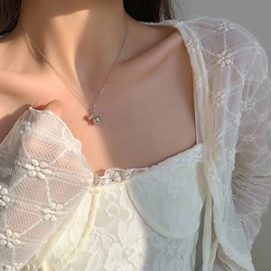 Detail of silver lily of the valley pendant necklace with natural sunlight on collarbone