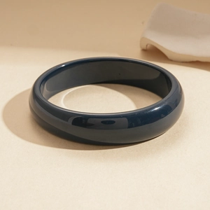 Detail of a navy blue resin bangle with a high-gloss finish and mirror reflections