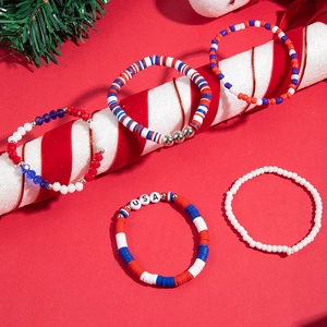 Close-up of five-piece Christmas beaded bracelets with Santa and elk charms on red background