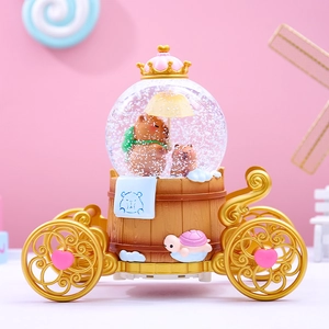 Close-up of a capybara musical snow globe inside a vintage golden carriage carriage decor